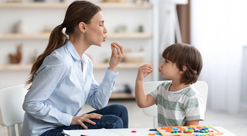 Parent and toddler sitting on floor playing with colorful blocks together, making eye contact and smiling during interactive play