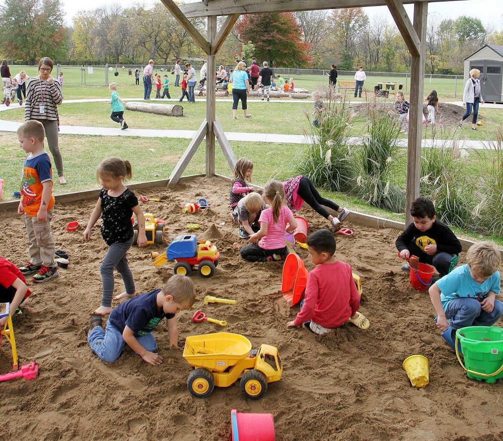Toddler exploring outdoors at a park surrounded by fall leaves and grass, engaging in outdoor play that supports healthy development
